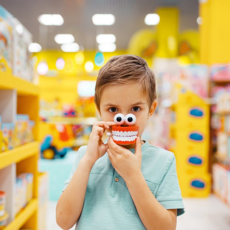 Boy holds jaw toy at the shelf in kids store